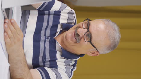 vertical video of home office worker old man fun working on laptop, using it.