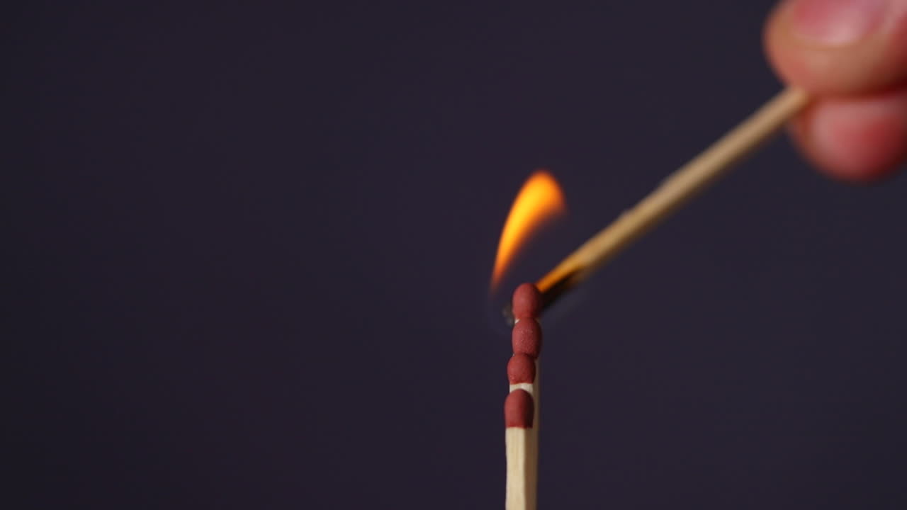 encendido de cuatro cerillas en primer plano, captura macro capturada desde el lado izquierdo y fuego desde abajo sobre fondo negro en cámara lenta a 120 fps