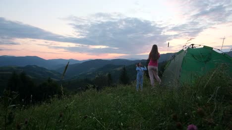 girls tourists are photographed at sunset in the mountains they are resting in a green tent girls tourists are photographed at sunset in the mountains they are resting in a green tent mountain trip