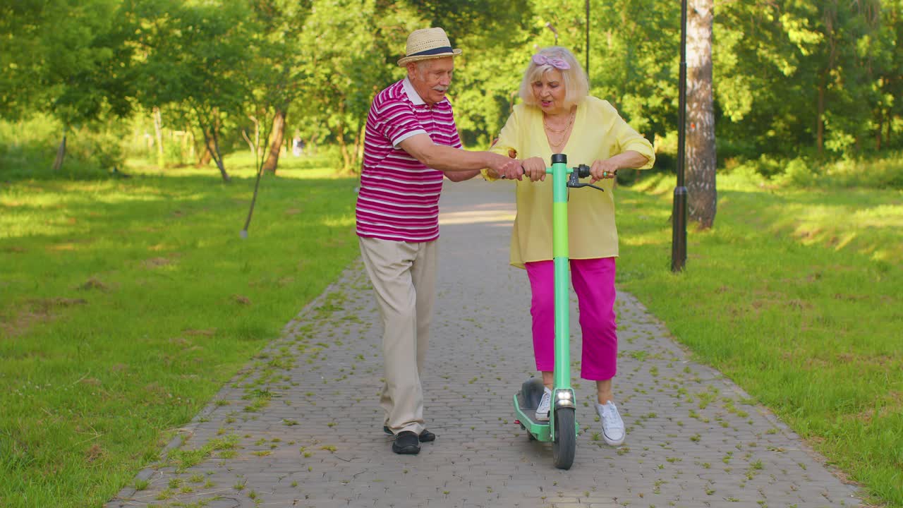 viejos turistas elegantes abuela, abuelo usando scooter eléctrico mientras viajan en el parque