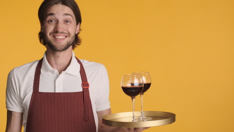 Caucasian-waiter-in-front-of-camera-on-yellow-background.