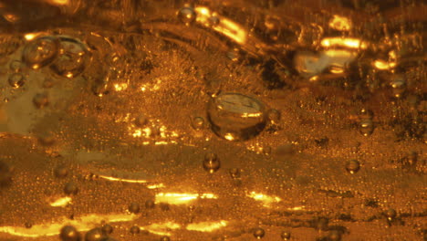 splashes light beer glass closeup. golden carbonated beverage swashing waving