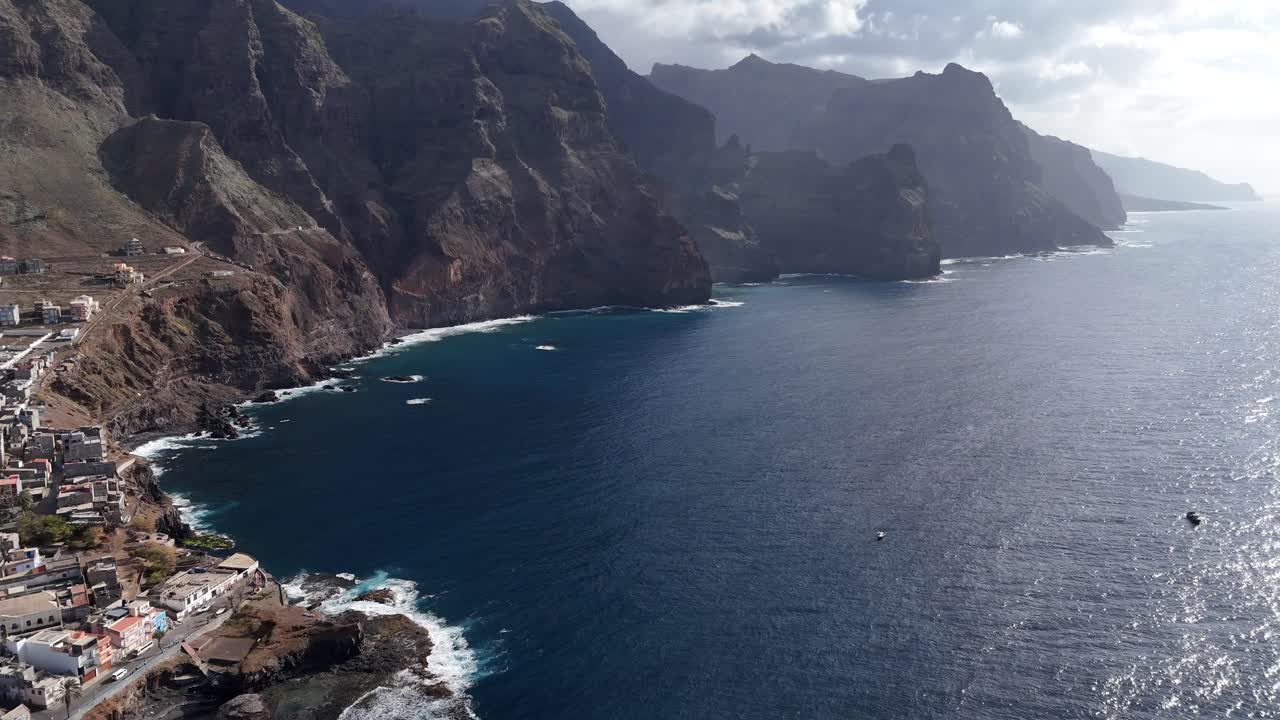Amplia toma aérea de los dramáticos acantilados y el pueblo de Ponta do Sol en Santo Antão, Cabo Verde. Metraje cinematográfico de dron de la costa volcánica encontrándose con el azul Océano Atlántico