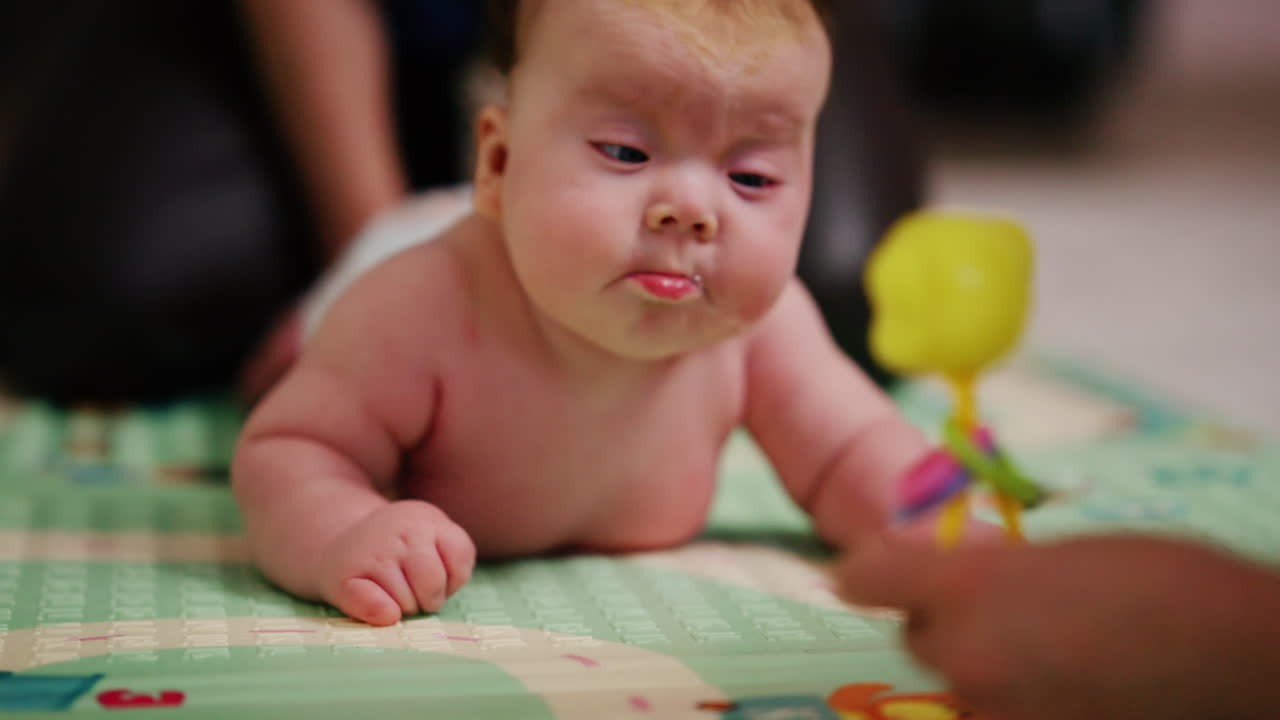 A small baby lying on their tummy and back on a padded surface