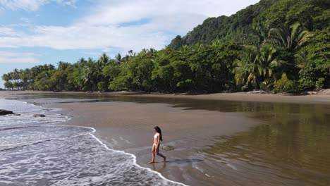 Camera-following-beautiful-young-woman-walking-on-beach-in-summer-sun