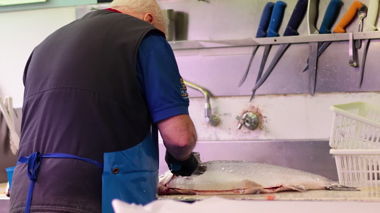 hombre quitando escamas de pescado en una estación de trabajo