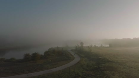 a 4k aerial drone view of an adult male walking into fog and mist in the early morning at exploration green in clear lake, houston, texas.