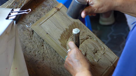 asian artisan handcrafting elephants on wood