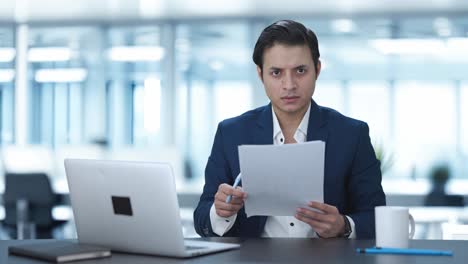 gerente indio enojado leyendo y firmando informes