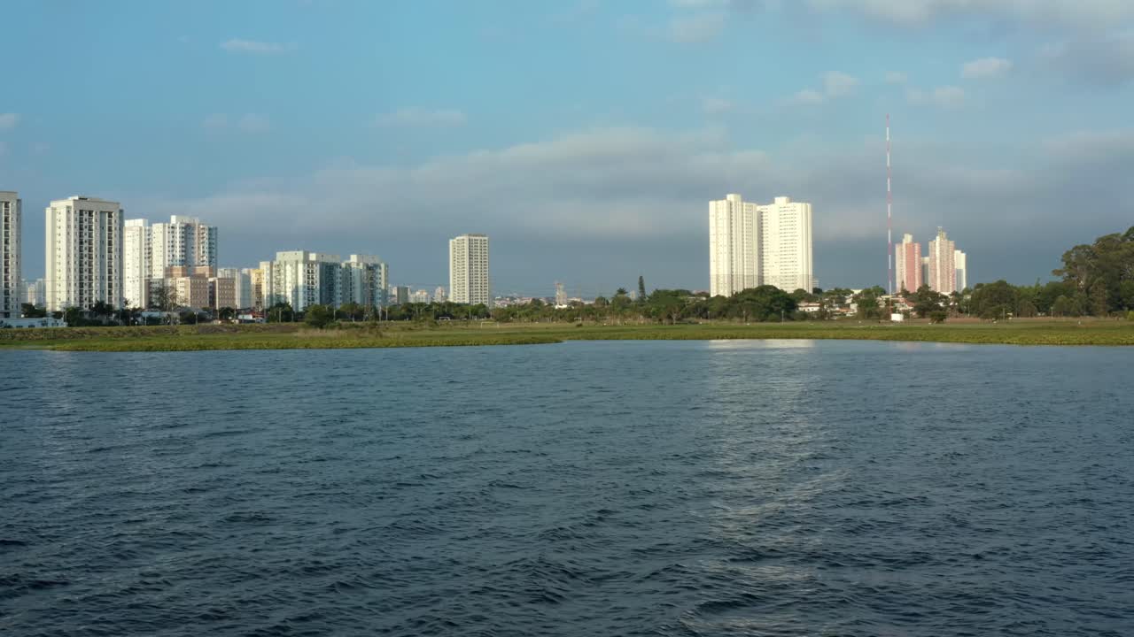 가을 저녁 배경에 잔잔한 바다와 고층 빌딩이 있는 인공 과라피랑가 저수지에서 브라질 상파울루 남쪽 소코로 인근의 공중 드론 돌리인 샷
