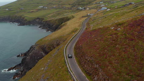 Vista-De-ángulo-Alto-De-La-Conducción-De-Un-Solo-Automóvil-En-Una-Estrecha-Carretera-Rural-A-Lo-Largo-De-La-Costa-Del-Mar.-Península-De-Slea-Head.-Irlanda