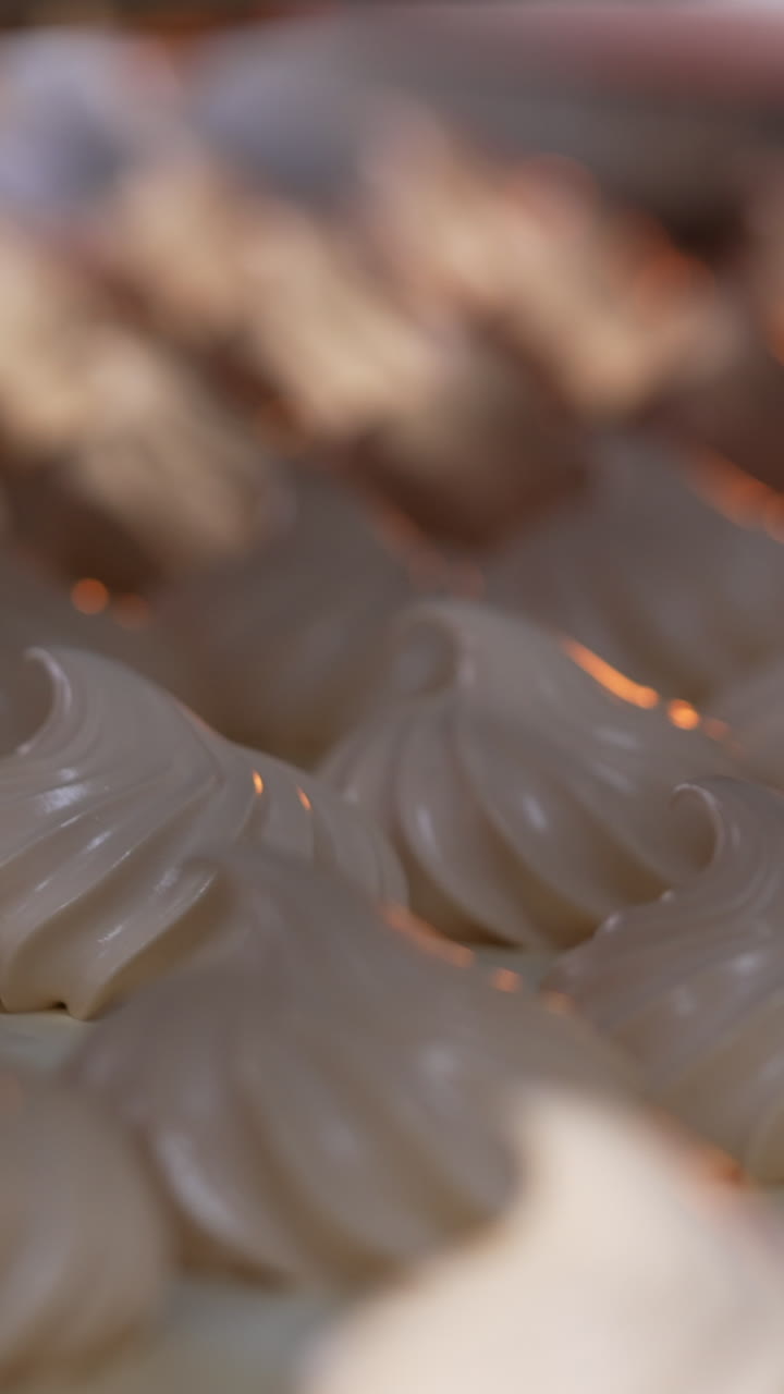 White creamy marshmallows identical in size and shape. Vanilla zephyr manufactured at food factory. Close up. Vertical video