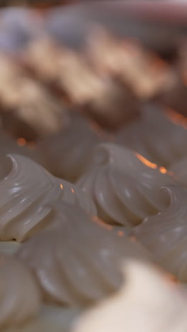 white creamy marshmallows identical in size and shape. vanilla zephyr manufactured at food factory. close up. vertical video