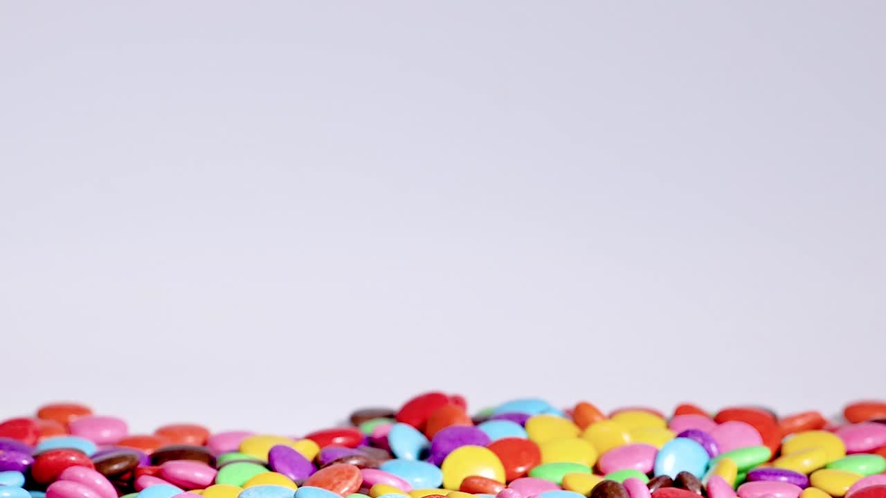 A variety of colorful candies fall into a growing, vibrant pile, creating a lively and playful scene.