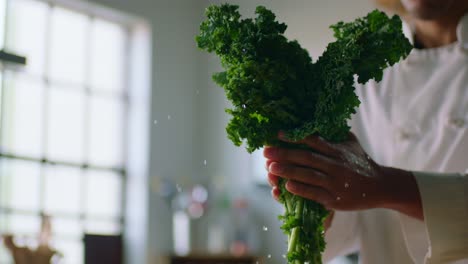 person shaking water off of a bunch of kale