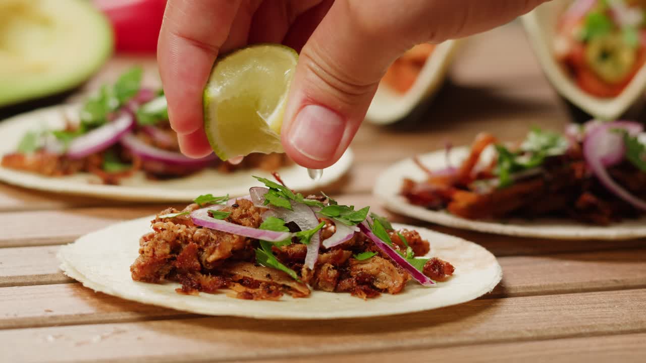 Hand squeezing lime juice onto delicious tacos