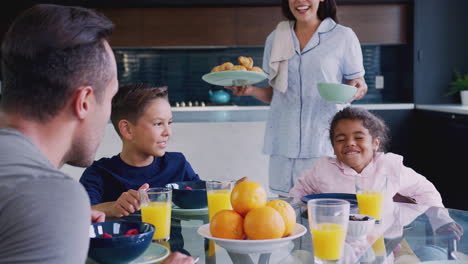 hispanic family sitting around table eating breakfast together