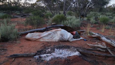 Ein-Buschmann,-Der-In-Seinem-Historischen-Ölfell-Swag-Im-Australischen-Outback-Neben-Einem-Kamin-Schläft