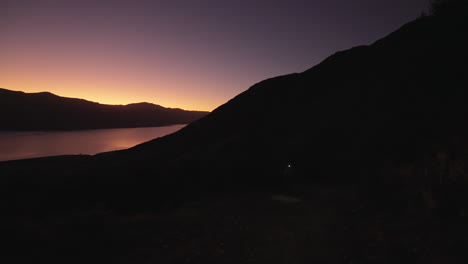 female hiker with head torch going up mountain before sunrise, new zealand