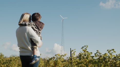 a female farmer shows her son a small wind farm in their family vineyard