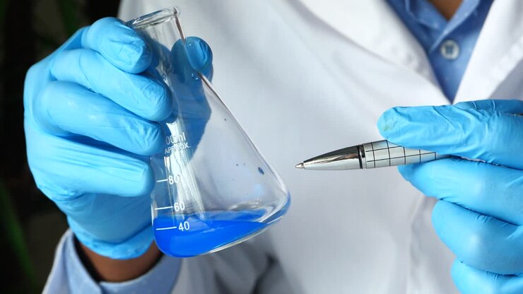 Scienziato che tiene una beuta con un liquido blu