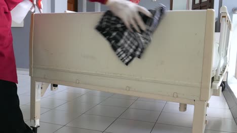작업자가 병원에서 환자의 침대 주변을 청소하고 있습니다.