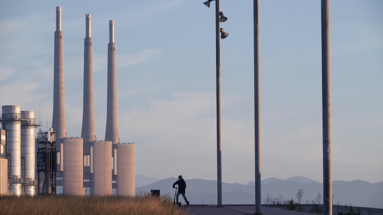 산업 풍경을 고민하는 남자는 일몰에 전기 스쿠터를 타고 내립니다.