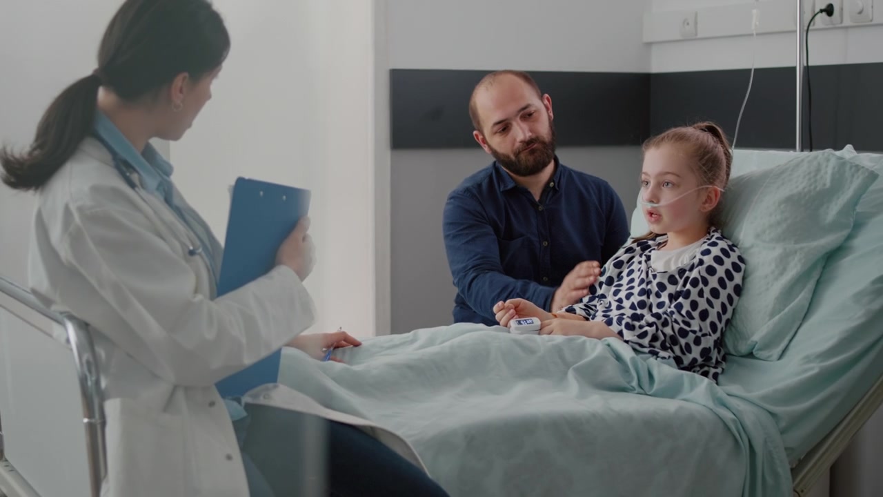 Lékař mluví s mladým pacientem a otcem v nemocničním pokoji
