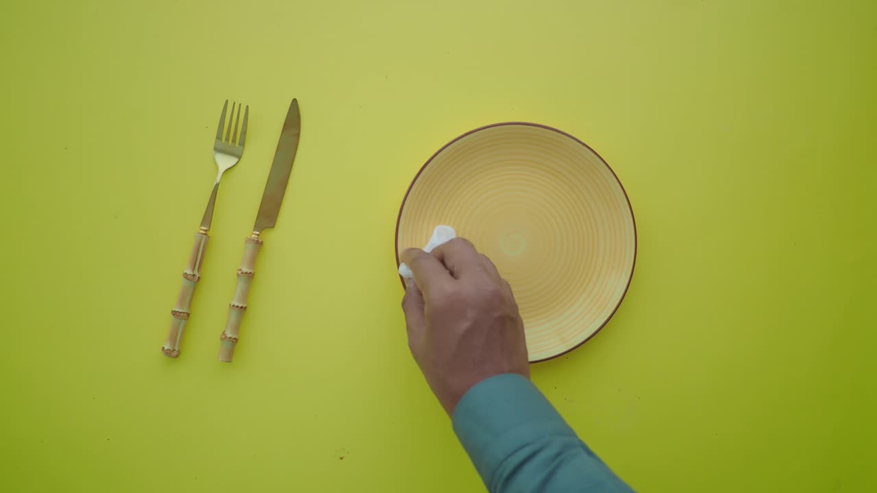 Table setting with plate, fork and knife being cleaned