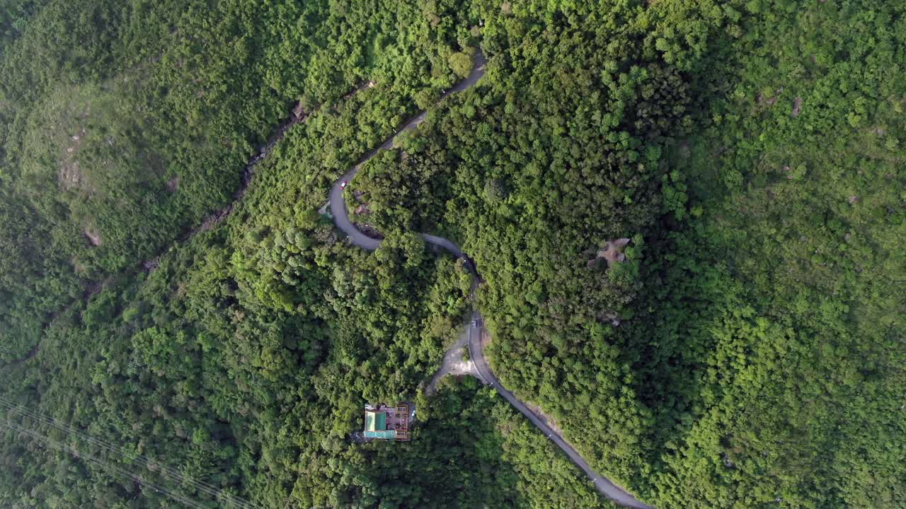 vista aérea de una estrecha y sinuosa carretera de montaña rodeada de una exuberante naturaleza verde