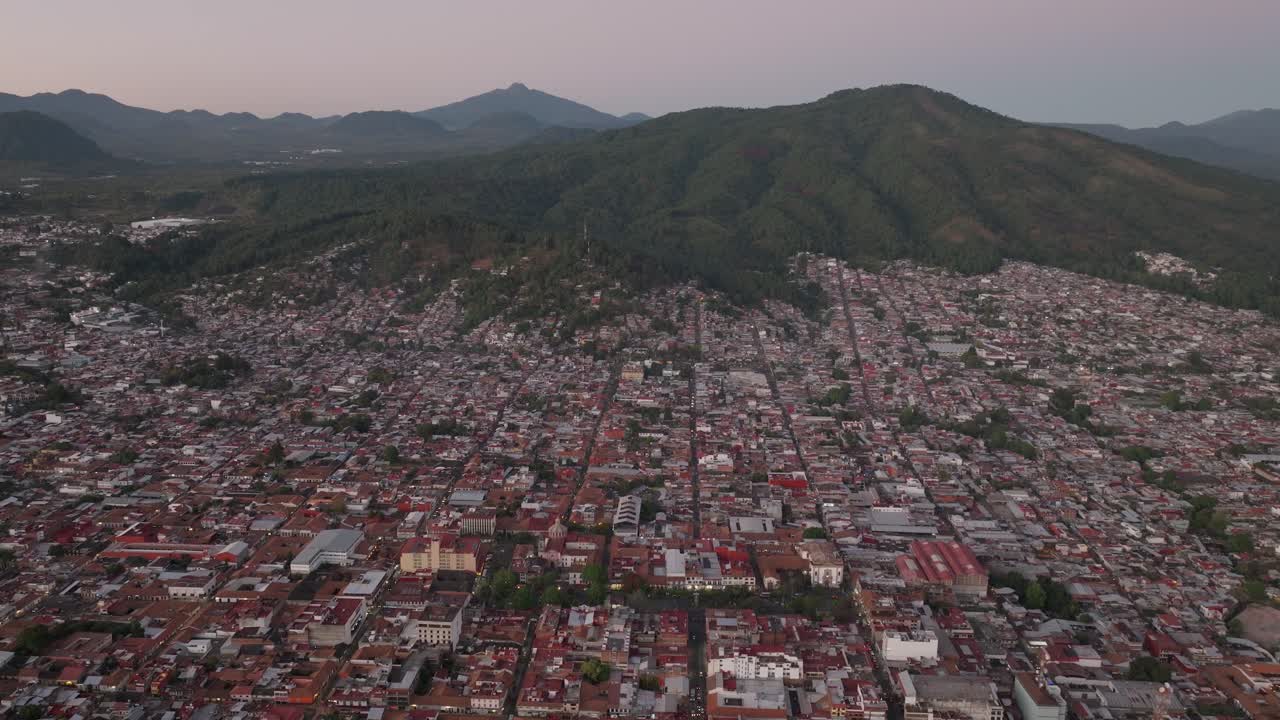 DRONE: REVEAL TILT UP SHOT OF URUAPAN MICHOACÁN DOWNTOWN AND MOUNTAINS AT SUNSET