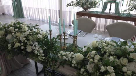 luxurious wedding table adorned with white floral arrangements, greenery, and blue candles