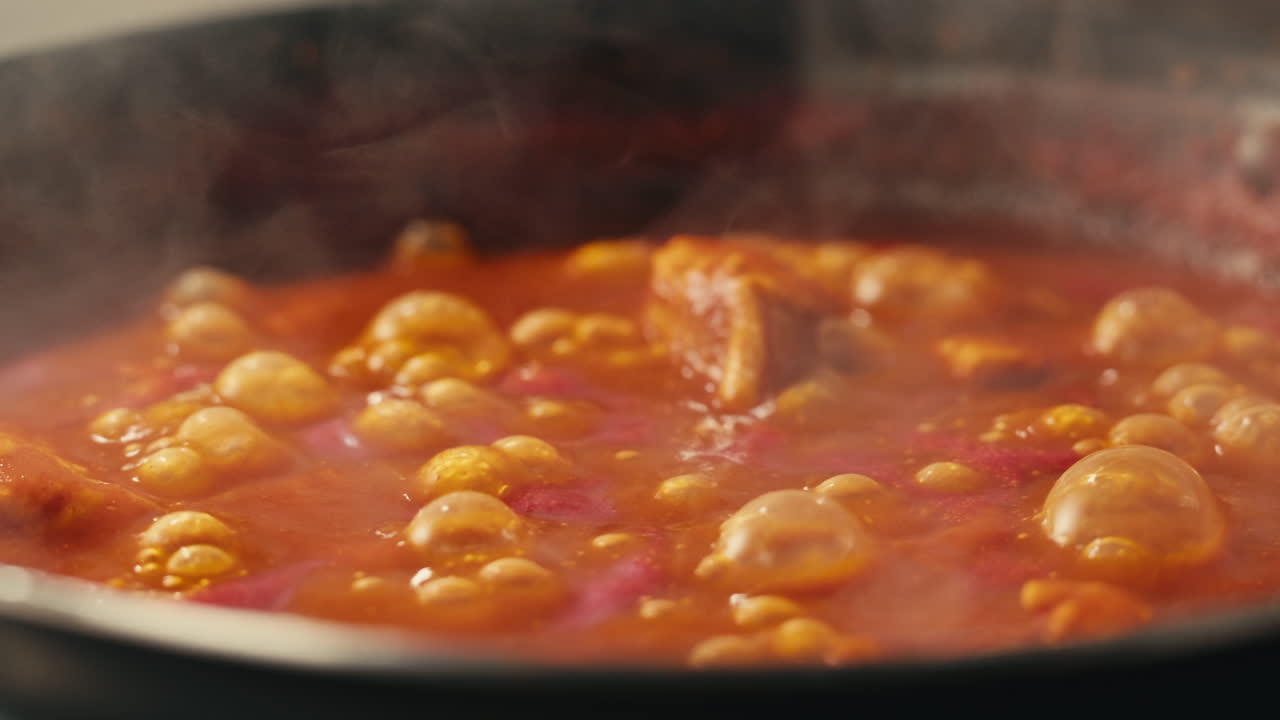 Chicken in tomato sauce is boiling on a frying pan with spices. Cooking tomato sauce curry with chicken fillet. Traditional Italian Mexican Asian dish. High quality studio shot for cafe, restaurant close up.