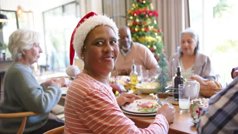 happy senior african american woman at christmas dinner table with diverse friends, slow motion