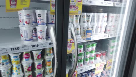 prices of yogurt and milk products inside a fridge illuminated, argentine pesos currency closeup, inflation concept at supermarket display