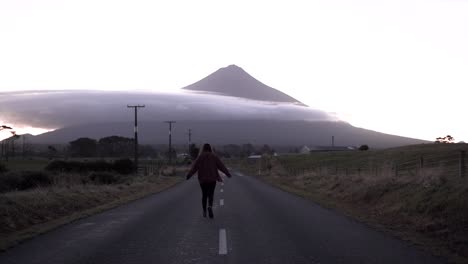 woman walking on road towards mountain