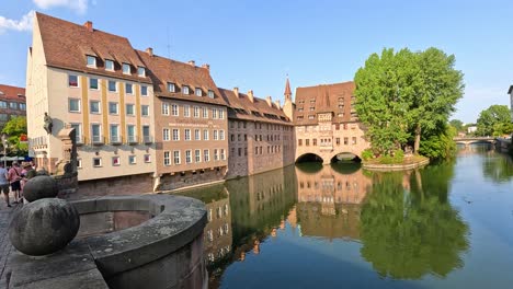 A steady daytime walk reveals historic buildings, canal reflections, and tourists in a medieval old town setting with bright natural lighting