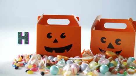 animation of halloween greetings over multiple candies and boxes in background