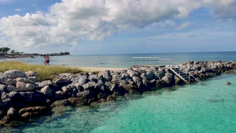 couple walking on a sandy beach near rocks and clear turquoise water 4k 30 fps