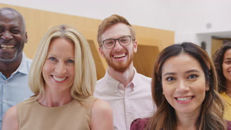 portrait of smiling multi-cultural business team standing in modern open plan office