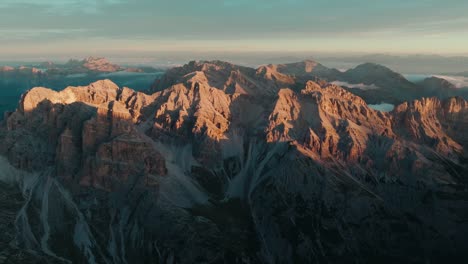 aerial view from left to right of the iconic punta sud di fanes, punta nord and monte ciaval peaks in the dolomites of cortina d'ampezzo, italy with the first light of sunrise