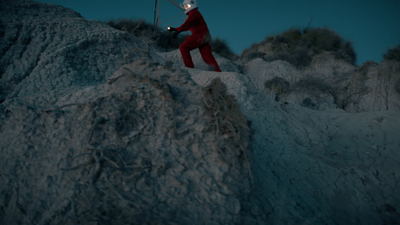 астронавт поднимается на гору и отчаянно кричит о помощи руками.