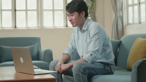 asian man greeting with colleagues in video conference call from laptop at living room, video in 4k