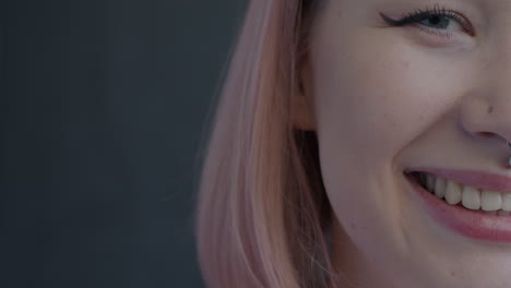 Close-up portrait of a smiling woman with pink hair