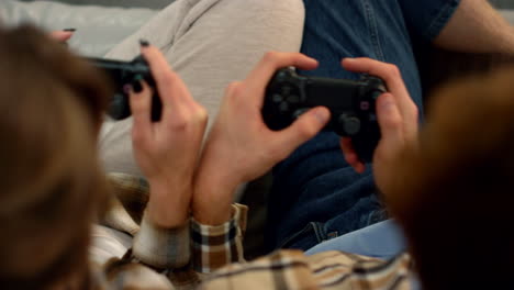 pareja de manos usando joysticks en casa de cerca. personas que se divierten jugando videojuegos