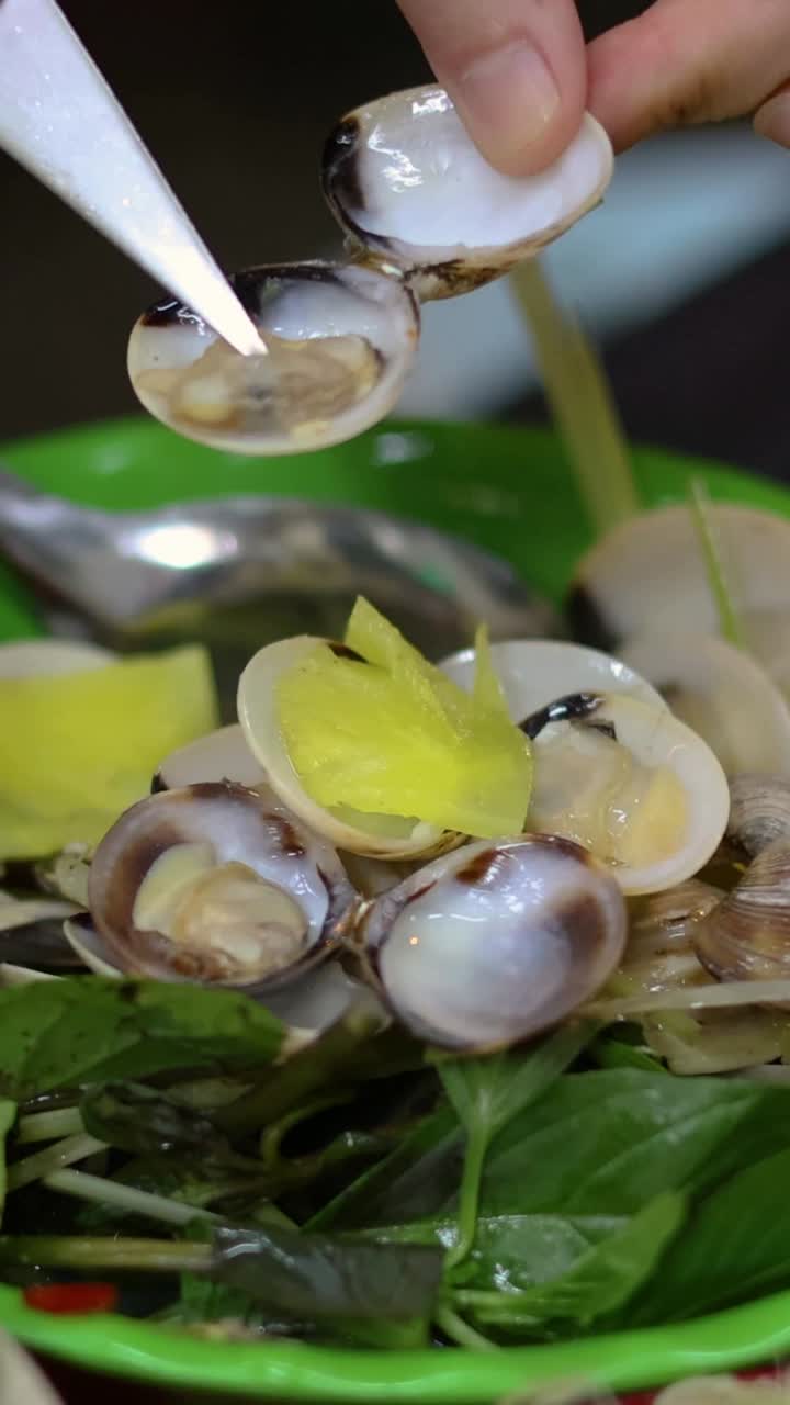 손은 그 위에 칼로 조개를 벗기고 있습니다.