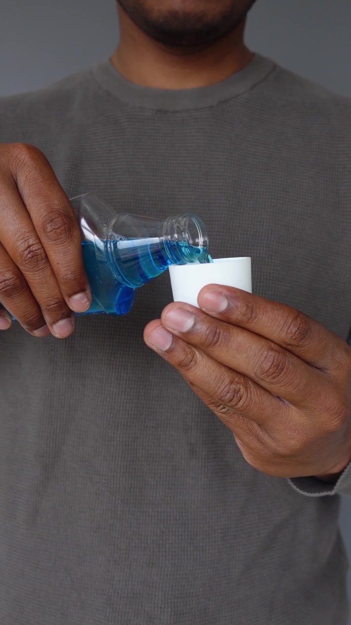 Man Pouring Blue Mouthwash into a Cap