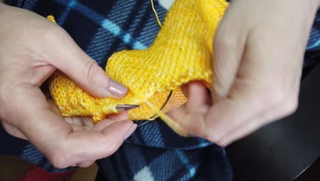 women's hands knit woolen jacket with knitting needles. top view, close-up of hands and knitting.