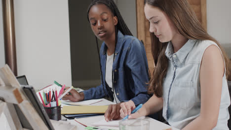 focused diverse teenage female friends studying at home using laptop and tablet