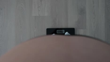 pov shot of a pregnant woman checking weight on a scale at 36+4 weeks of pregnancy
